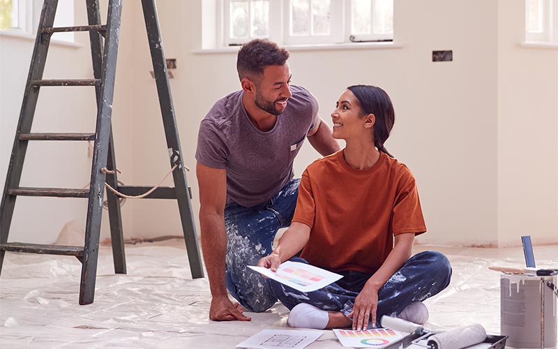 Couple sat on the floor of their new home surrounded by decorating products