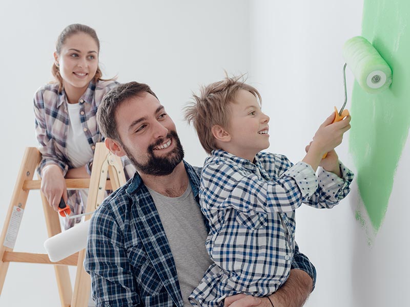 Small child helps a couple paint a wall in their new home